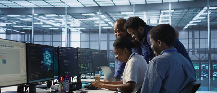 Data center coworkers laughing, having fun while maintaining company network infrastructure. Server hub colleagues enjoying time together in office, telling jokes, having conversation, camera A